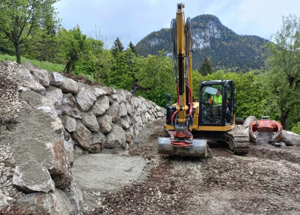 Kettenbagger vor einer neu gesetzten Steinmauer