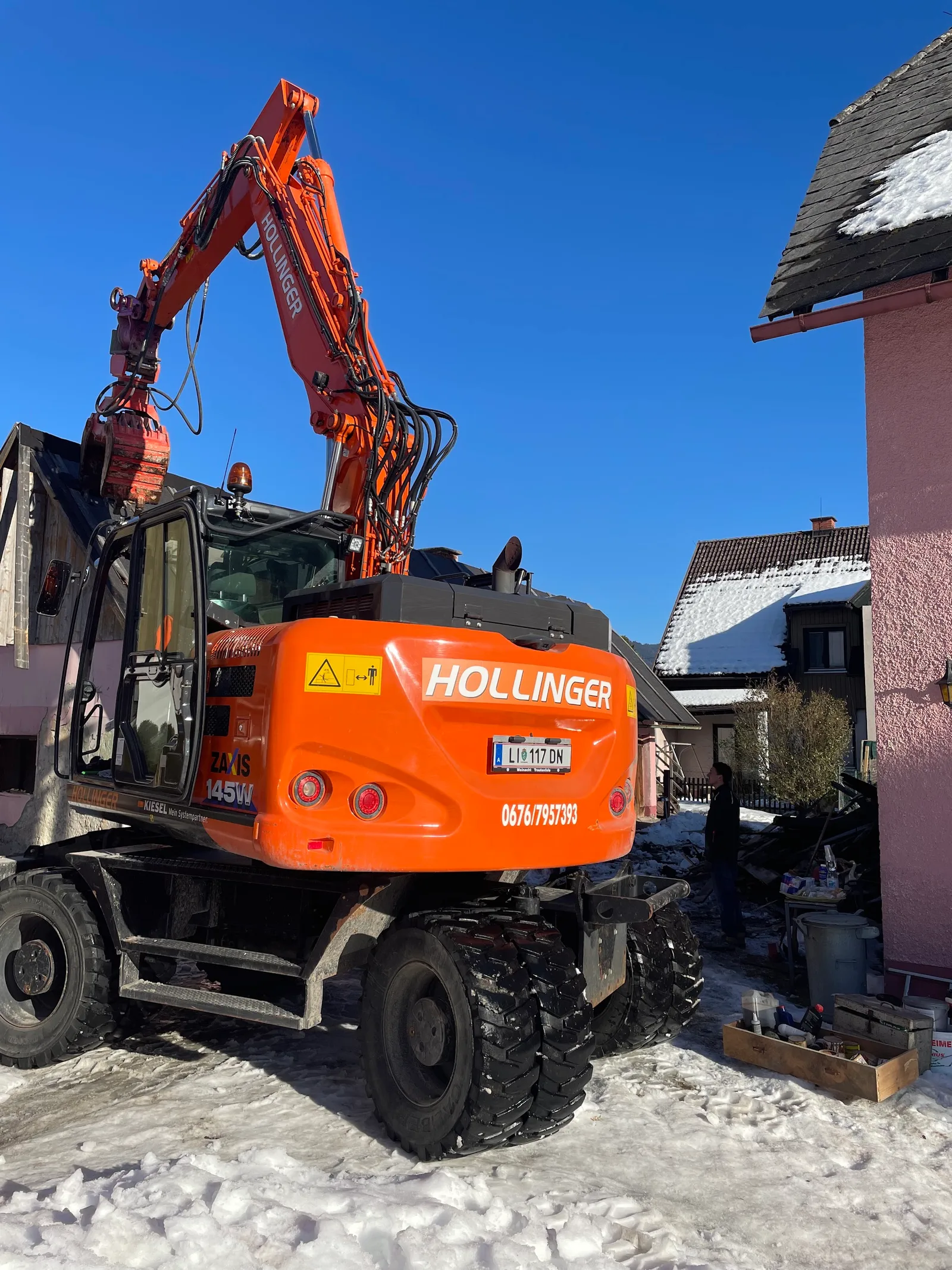 Beschrifteter Mobilbagger auf einer winterlichen Baustelle